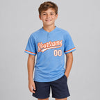 Custom Light Blue Two Button Softball Jersey with White and Orange Lettering youth size worn by child model