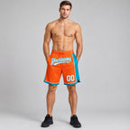 Custom Orange Authentic Basketball Shorts with White and Teal Lettering worn by male model