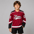 Custom Maroon Lace Neck Hockey Jersey with White and Black Lettering youth size worn by child model